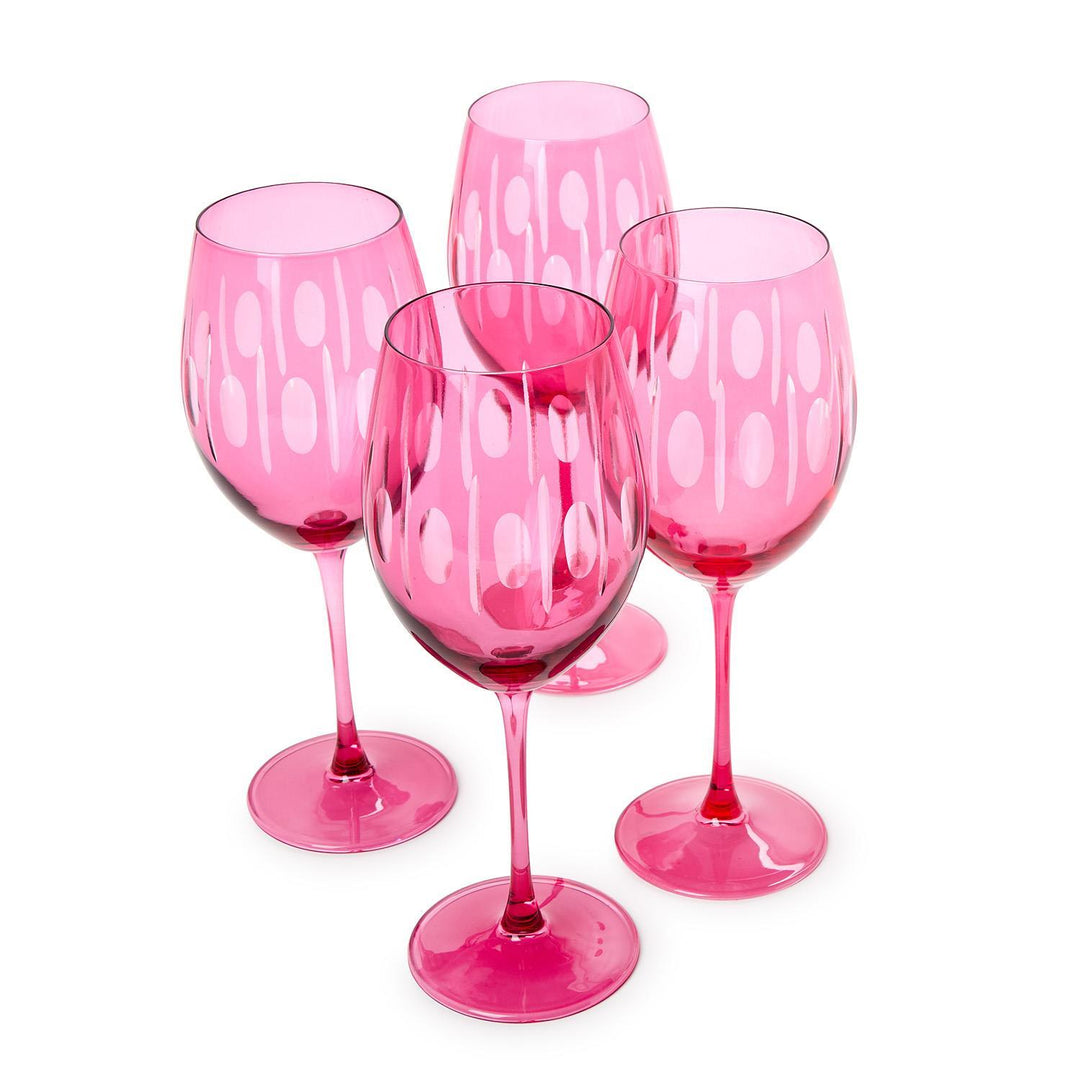 Glassware set of four vibrant fuchsia wine glasses on a white background featuring etched white oval patterns, vertical stripe details, and long slender stems