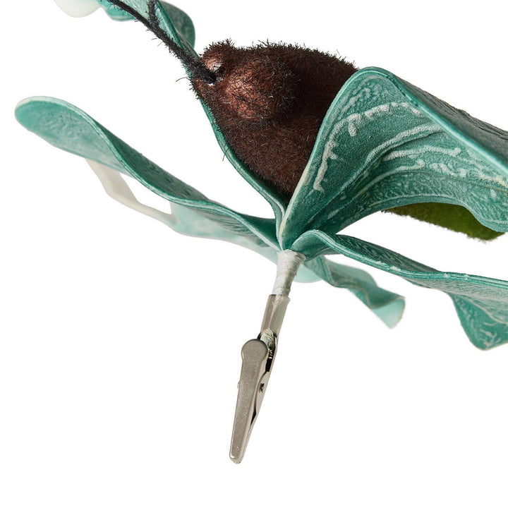 Decorative craft ornament of a clip-on moth featuring a fuzzy brown body and textured teal-green wings with white veining attached to a silver metal clip against a white background