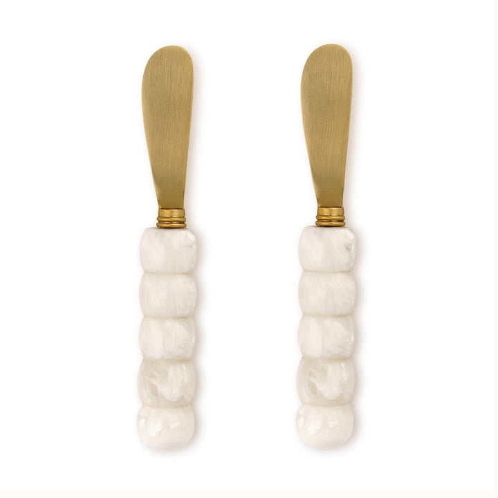 Stainless steel gold-toned spreader knives featuring five-segmented white marbled resin handles and rounded matte blades displayed on a white background