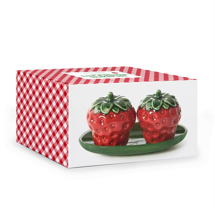 Ceramic strawberry salt and pepper shakers on a green leaf-shaped tray inside a red and white gingham box featuring glossy red glazes and textured green leaf caps