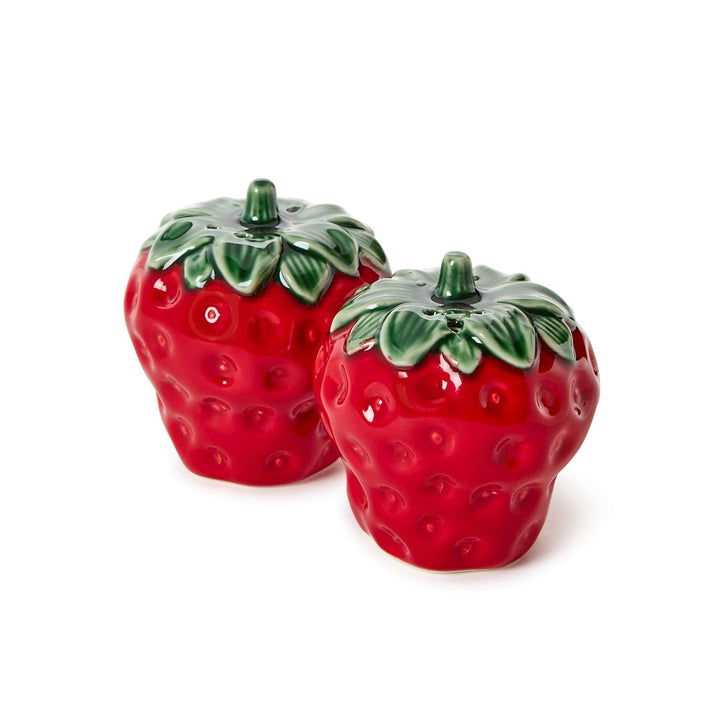 Ceramic strawberry salt and pepper shakers on a white background featuring vibrant red glossy glazes, textured seed indentations, and dark green leaf-shaped caps with stems