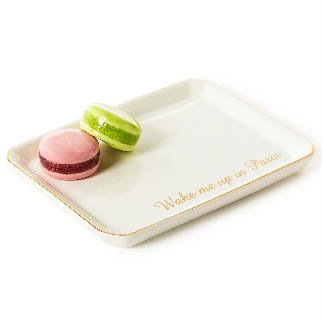 Ceramic trinket tray featuring a pink and lime green macaron next to gold cursive text reading Wake me up in Paris with a delicate gold-gilded rim