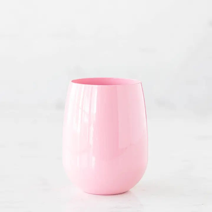 Studio photograph of a glossy pink stemless tumbler on a white marble surface featuring a reflective finish and soft pastel tones