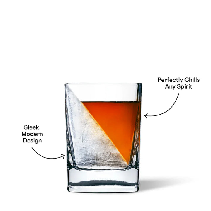 Commercial product photograph of a whiskey glass on a white studio background featuring a golden-amber spirit chilled by a large diagonal ice wedge with black promotional text and curved arrows