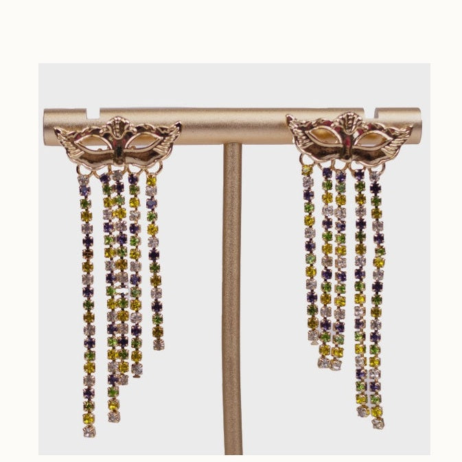 Photograph of gold-toned Mardi Gras masquerade mask earrings on a jewelry display stand featuring cascading fringe strands of purple, green, and gold rhinestones in staggered lengths