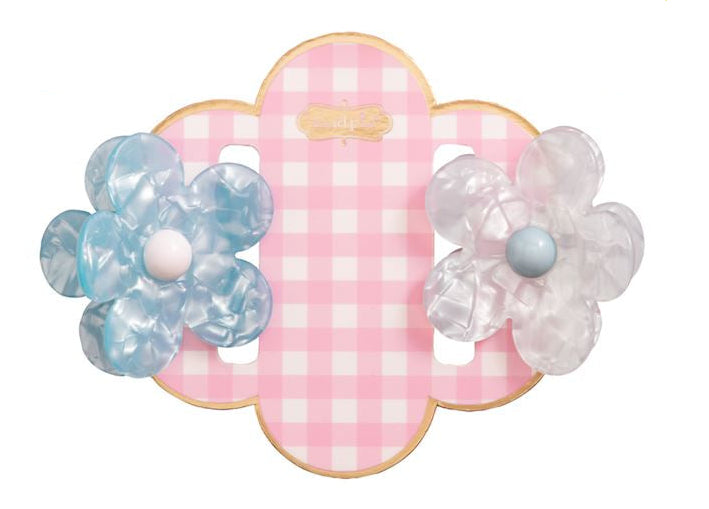 Cellulose acetate hair accessories by Machete featuring two mini flower claw clips in marbled cerulean and iridescent white displayed on a pink gingham quatrefoil card with a gold-rimmed edge
