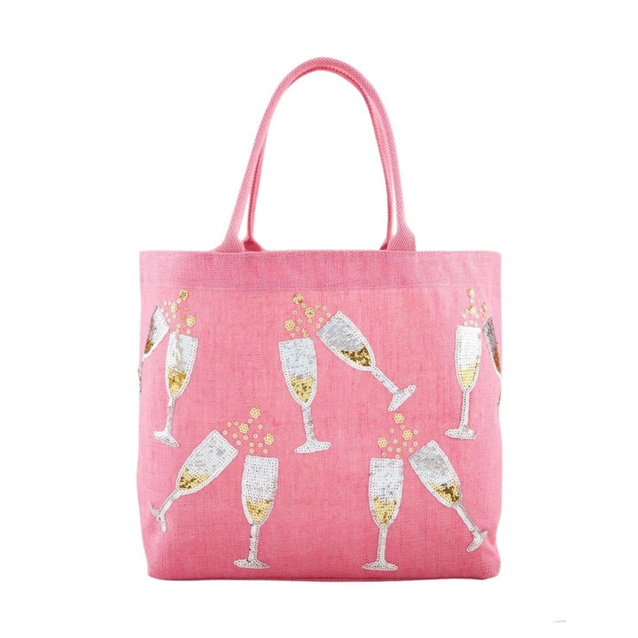 Woven pink jute tote bag featuring a festive pattern of silver sequined champagne glasses with gold centers and yellow beaded bubbles against a white studio background