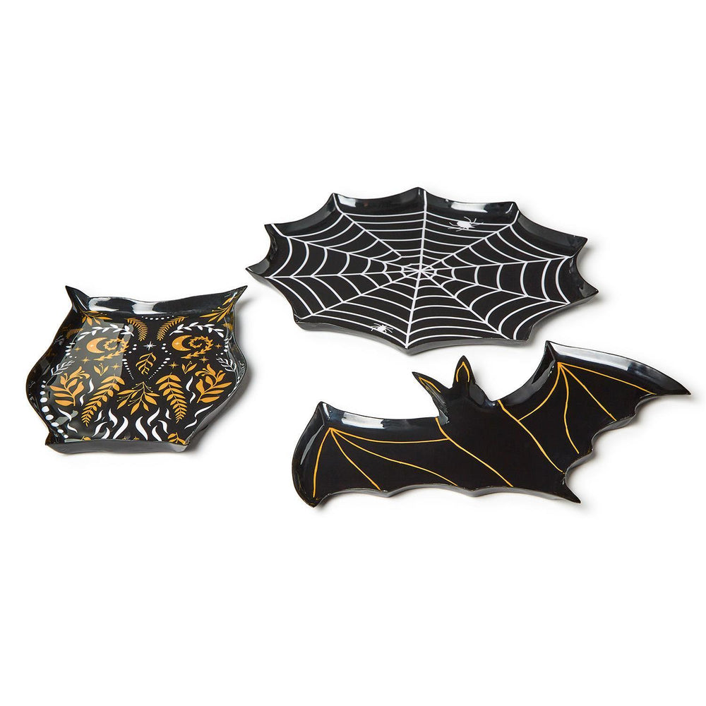 Melamine Halloween-themed serving trays featuring a white-lined spider web, a black owl with gold celestial patterns, and a bat with metallic gold wing outlines on a plain white background