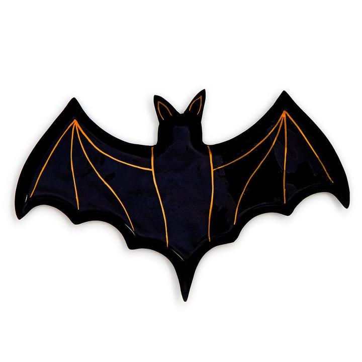 Ceramic decorative dish shaped like a bat centered on a white background featuring a glossy black finish and metallic orange skeletal wing accents