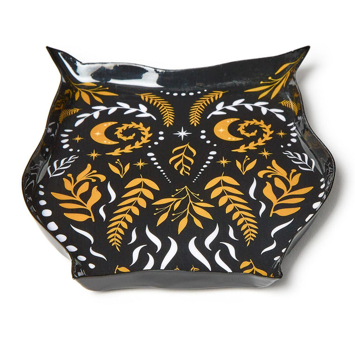 Ceramic owl-shaped trinket dish on a white background featuring a glossy black glaze embellished with golden crescent moon eyes, symmetrical white botanical sprigs, and intricate celestial star patterns