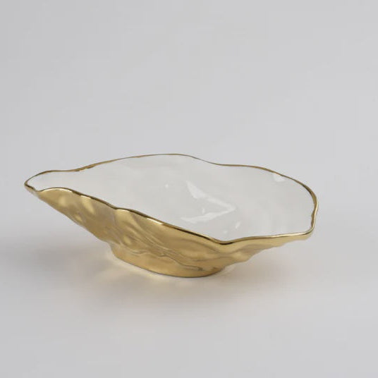 Ceramic oyster shell bowl by Pampa Bay on a grey background featuring a textured gold metallic exterior and a polished white interior with a wavy scalloped edge