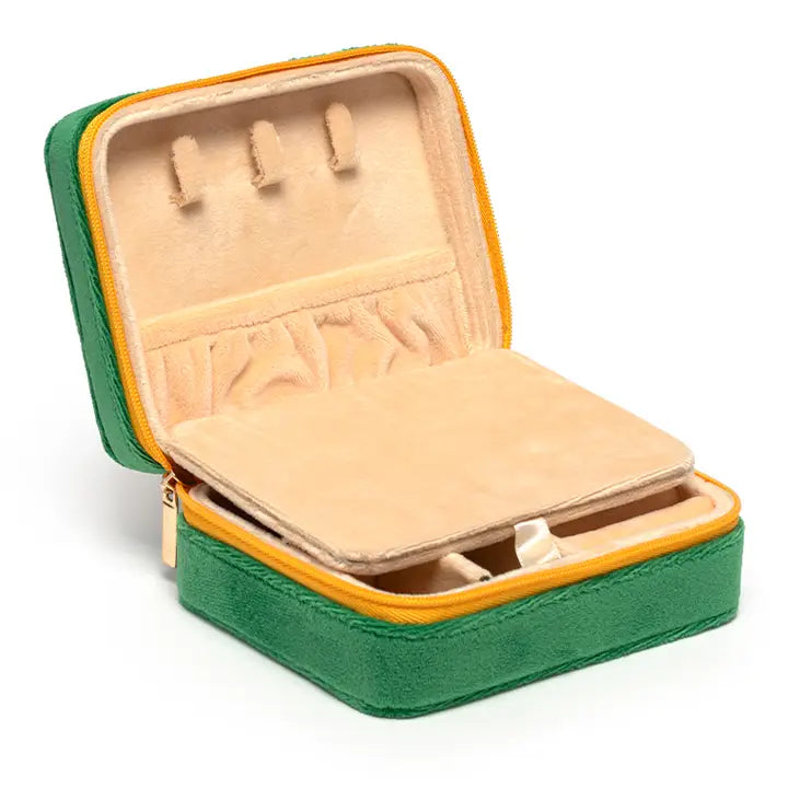 Product photography of an open forest green velvet jewelry box on a white background featuring a vibrant yellow zipper, three tan interior necklace hooks, and a plush cream-colored lining