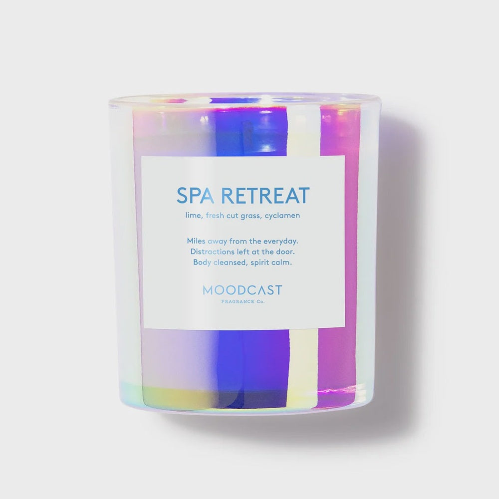 Studio product photograph of a Moodcast Fragrance Co. Spa Retreat scented candle featuring a vibrant iridescent holographic glass jar and a white label listing notes of lime, fresh cut grass, and cyclamen against a neutral studio background