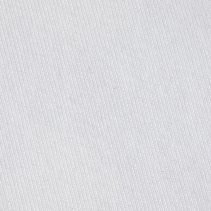 Photograph of white cotton twill fabric featuring a prominent diagonal weave pattern and tiny stray dark fibers on its textured surface