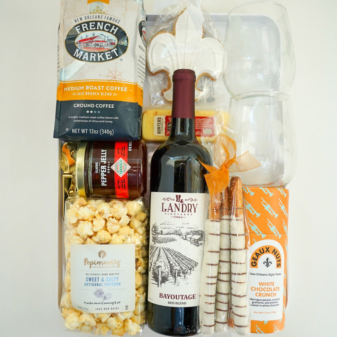 Gift basket with wine, coffee, popcorn, and other snacks on a white background
