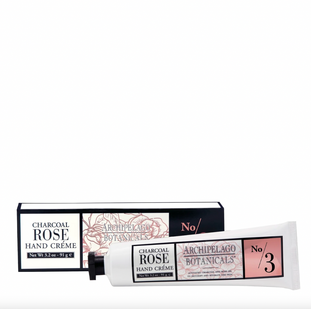 Commercial product photography by Archipelago Botanicals of Charcoal Rose Hand Crème displayed on a white background featuring a white squeeze tube with a black octagonal cap and a box decorated with pink floral line art and the No 3 label