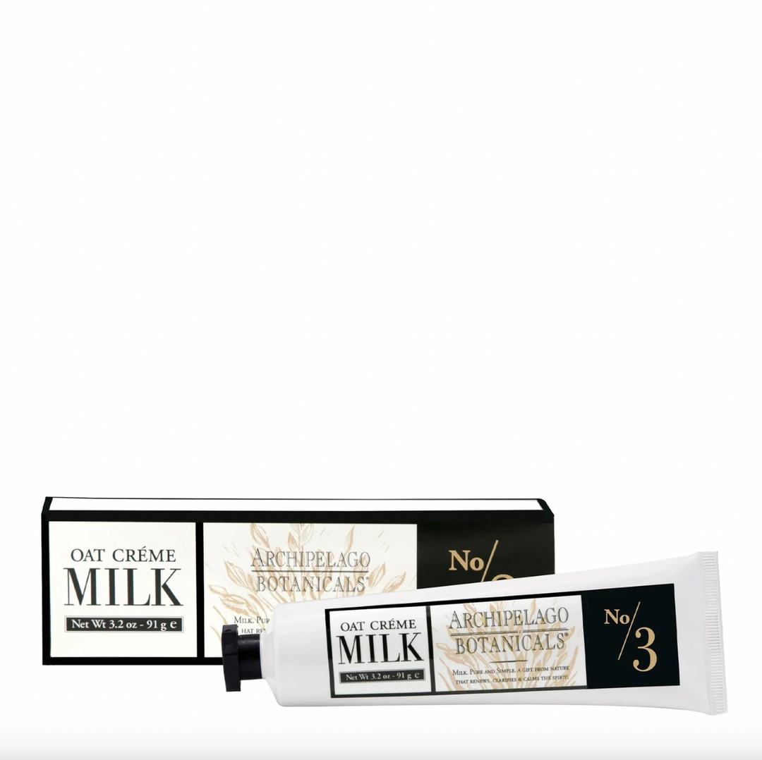 Product photography by Archipelago Botanicals of an Oat Crème Milk hand cream tube and packaging box on a white background featuring the No 3 branding with gold botanical line art and a matte black screw cap