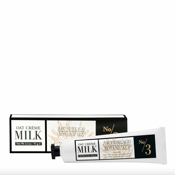 Product photography by Archipelago Botanicals of an Oat Crème Milk hand cream tube and packaging box on a white background featuring the No 3 branding with gold botanical line art and a matte black screw cap