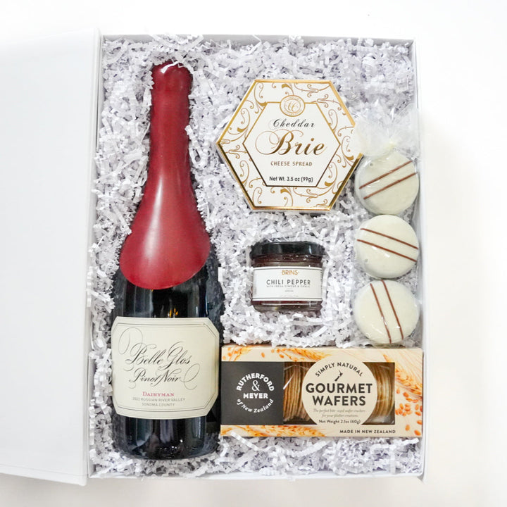 Gift set with a bottle of wine, cheese, and cookies on ice