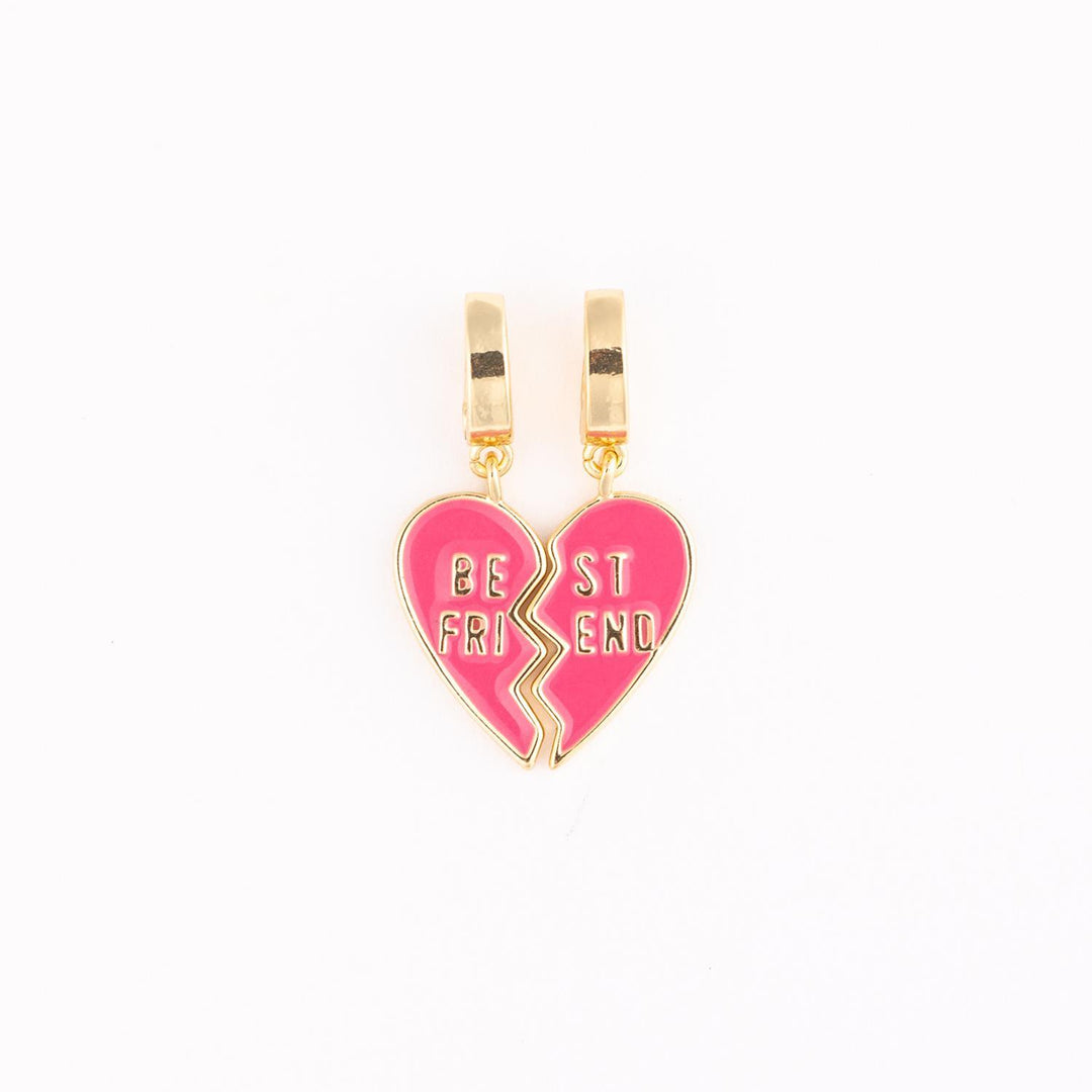 Gold-plated and pink enamel charms featuring two interlocking heart halves with the words BE ST FRI END engraved in gold against a plain white studio background