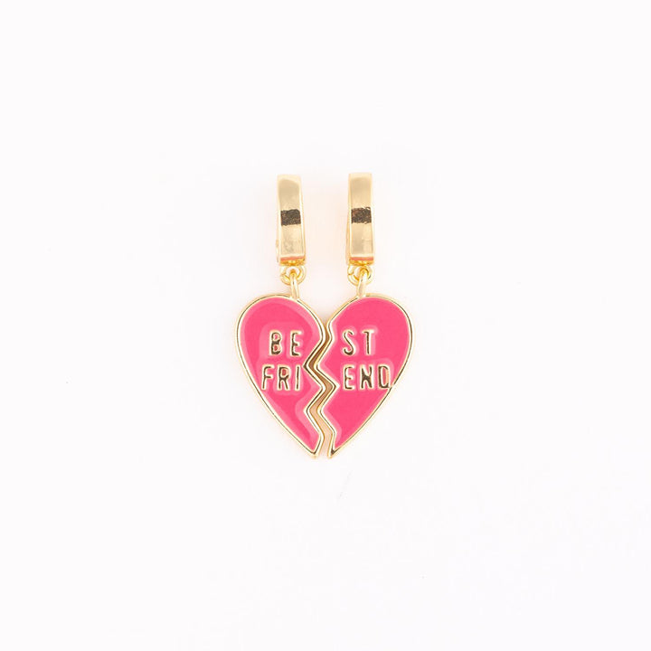 Gold-plated and pink enamel charms featuring two interlocking heart halves with the words BE ST FRI END engraved in gold against a plain white studio background