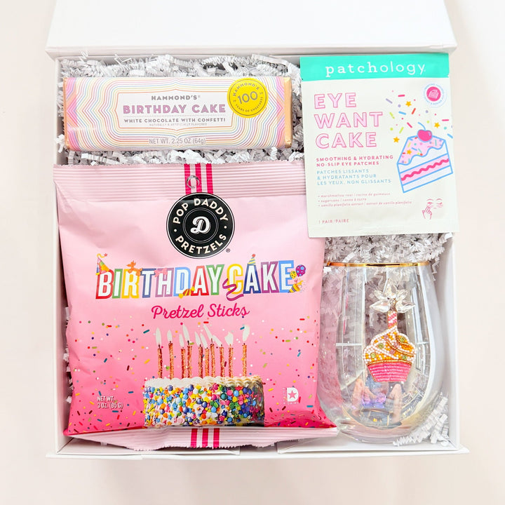 Packaged birthday-themed items including a roll of paper, a box of stickers, and a small container on a white background.