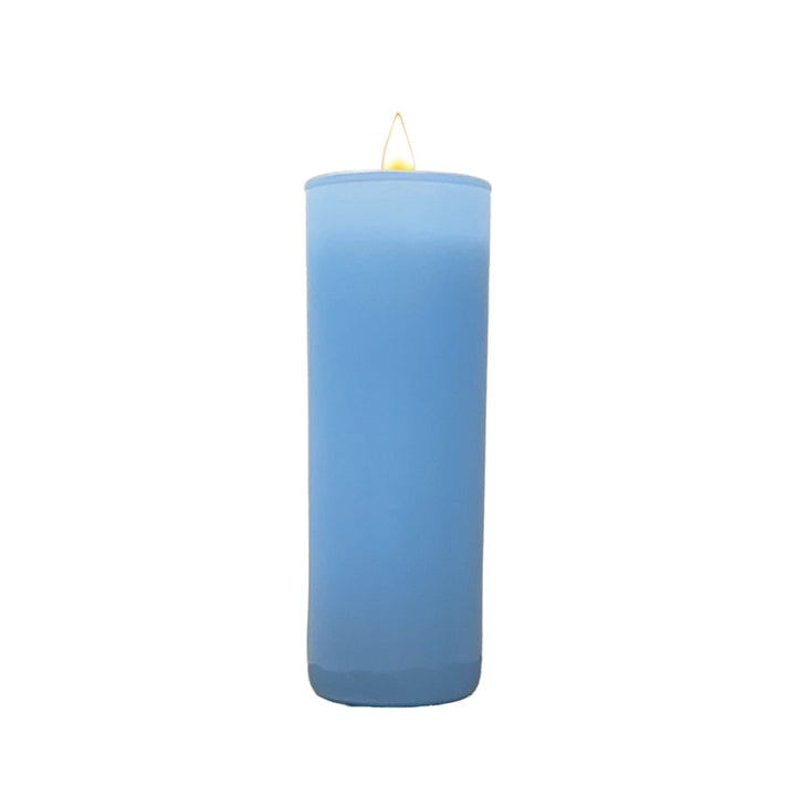 Photograph of a tall light blue pillar candle centered against a white background featuring a small glowing yellow flame and a smooth cylindrical wax body