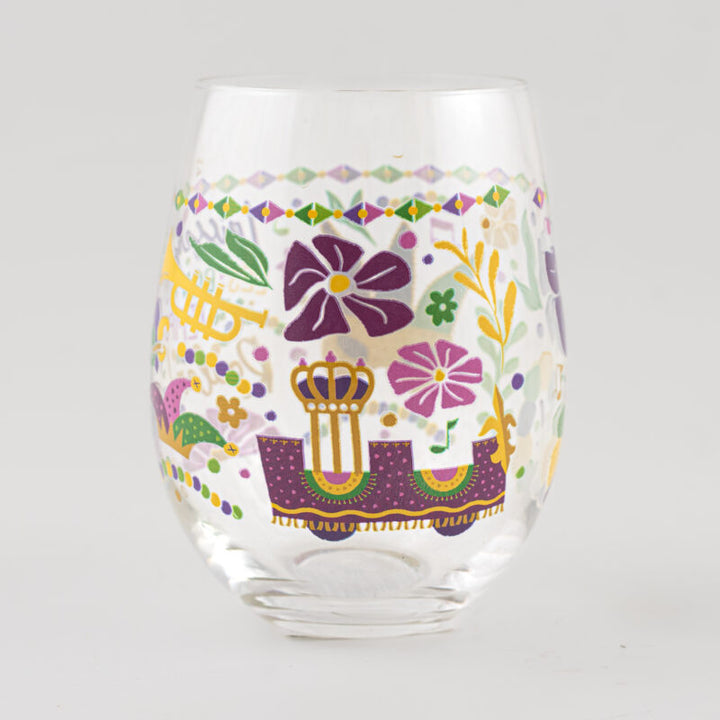 Glass tumbler featuring New Orleans Mardi Gras motifs including a purple parade float with a golden crown, a yellow trumpet, and a colorful jester hat accented with purple and green floral patterns