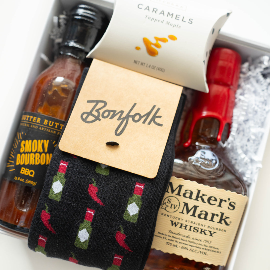 Commercial photograph of a curated bourbon gift box featuring a bottle of Maker&