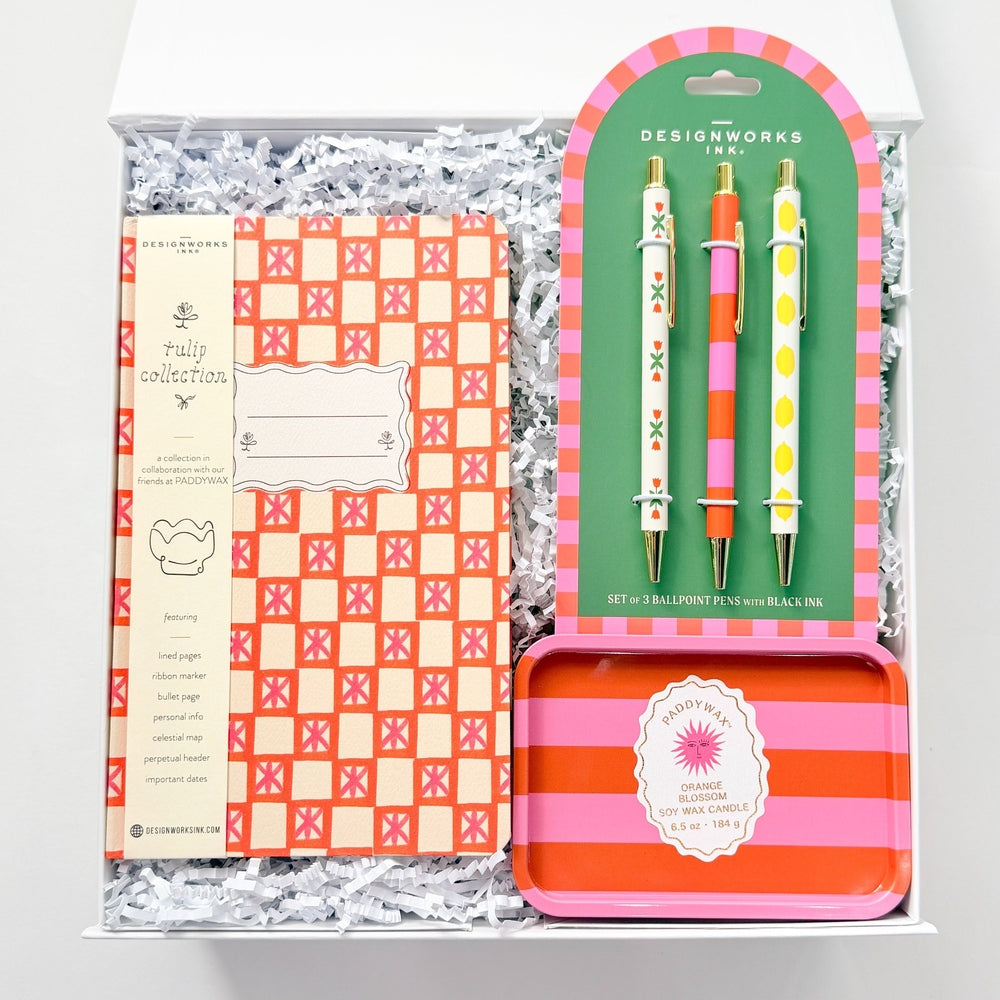 Stationery set with checkered notebook, colorful pencils, and a striped tin in a box on a white background