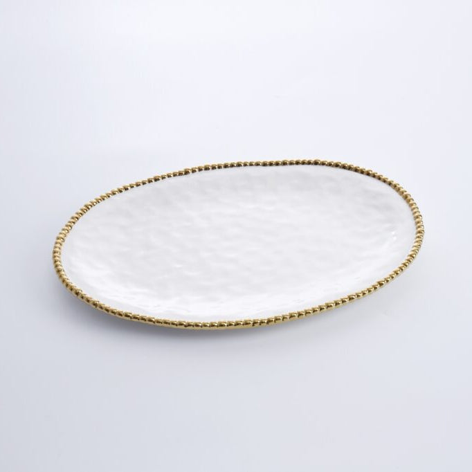 Ceramic oval serving platter featuring a textured white hammered surface and a metallic gold beaded rim set against a minimalist white studio background