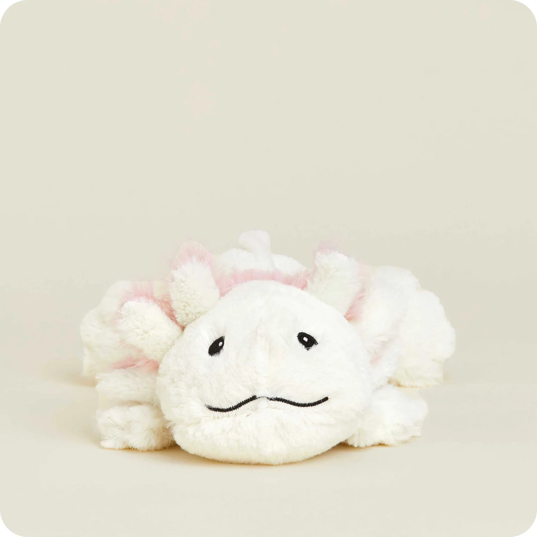 Plush toy of a white axolotl resting on a neutral cream studio background featuring soft pink feathery gills, small black embroidered eyes, and a gentle wavy stitched smile