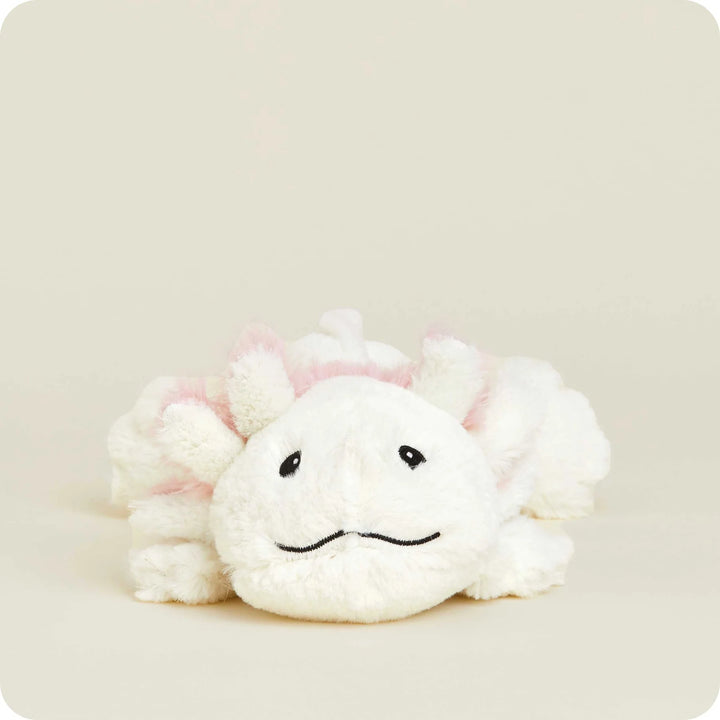 Plush toy of a white axolotl resting on a neutral cream studio background featuring soft pink feathery gills, small black embroidered eyes, and a gentle wavy stitched smile