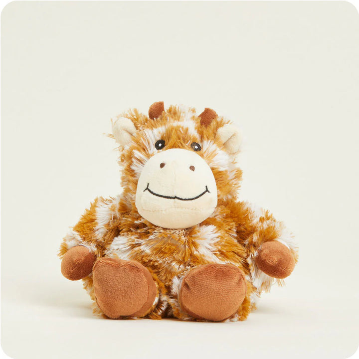 Plush stuffed toy by Warmies of a sitting giraffe on an off-white background featuring mottled orange-brown and white faux fur, a cream-colored muzzle with a stitched black smile, and small brown ossicones