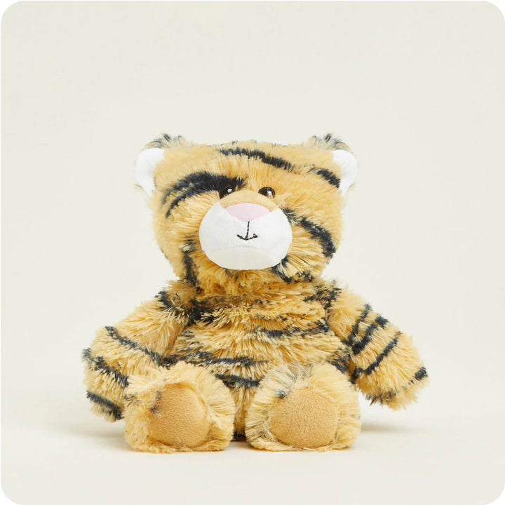 Plush toy of a tiger cub sitting on a plain cream background featuring shaggy tan fur with black stripes, white inner ears, and a white muzzle with a pink nose