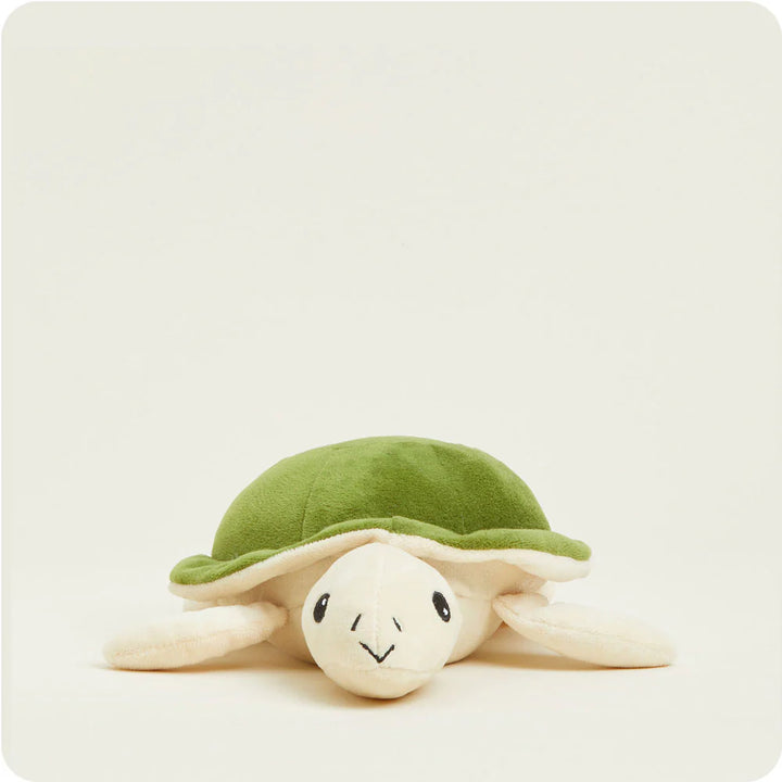 Plush toy by Jellycat of a Tumbletuft Turtle on a minimalist off-white background featuring a moss green textured shell, cream-colored flippers, and delicate black stitched facial details