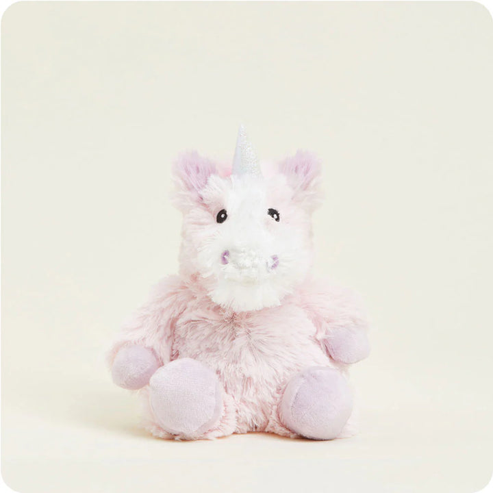 Studio photograph of a plush pink unicorn sitting against a neutral ivory backdrop featuring a shimmering silver horn, shaggy pastel fur, and soft lavender hooves