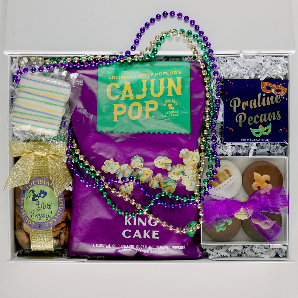 Photograph of a Louisiana Mardi Gras themed gift box from New Orleans featuring Cajun Pop King Cake popcorn, festive purple, green, and gold beads, and chocolates decorated with iconic fleur-de-lis and mask motifs tied with a shimmering gold ribbon