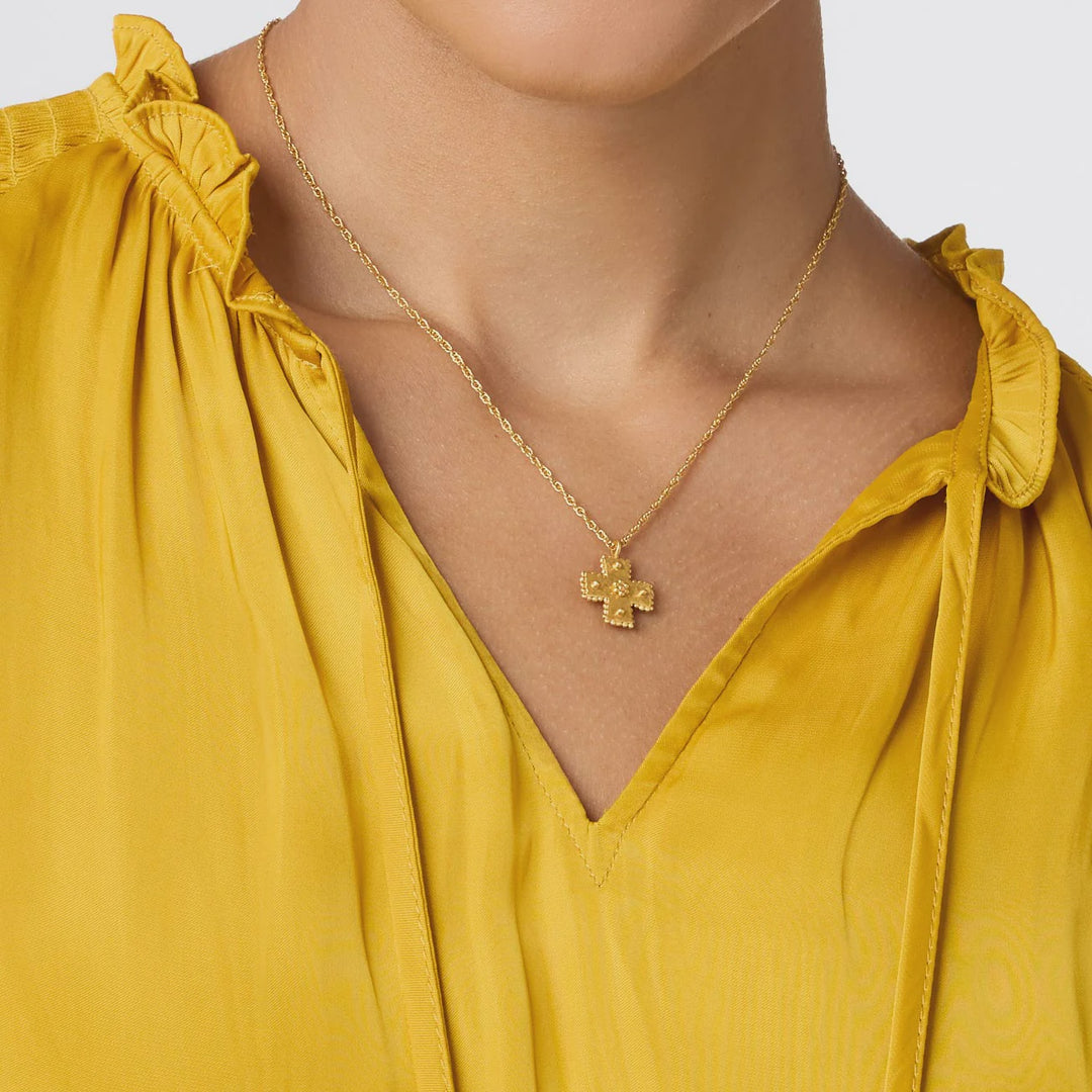 Gold jewelry photograph featuring a textured cross pendant worn on a woman&
