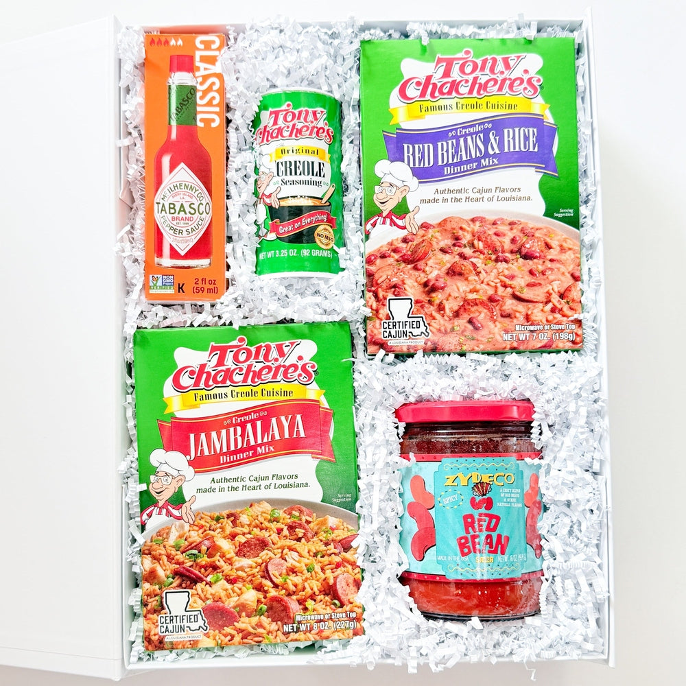 Product photograph of a Louisiana-themed gift box featuring iconic Tabasco hot sauce and Tony Chachere’s Creole mixes nestled in white shredded paper with vibrant green packaging and a glass jar of Zydeco red bean sauce