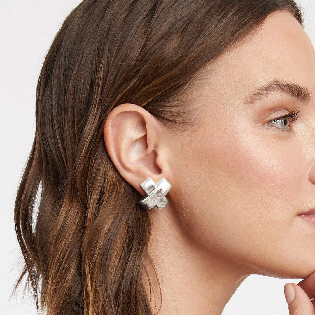 Silver hammered metal earring in an X-shape worn on a woman&