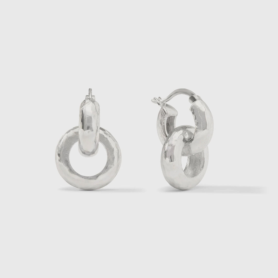 Sterling silver jewelry interlocking double hoop earrings displayed on a plain grey studio background featuring a unique hand-hammered texture and polished metallic finish