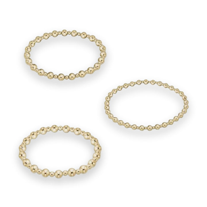 Jewelry product photography of three gold beaded bracelets on a neutral studio background featuring polished spherical beads of varying sizes with high-shine reflective surfaces