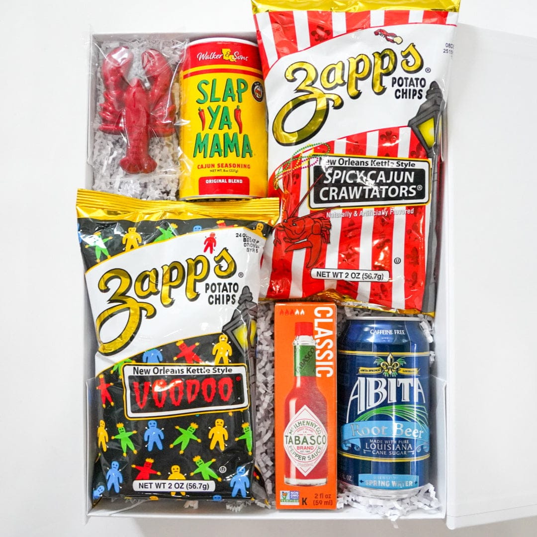 Assorted snack items including Zapp's potato chips and Slap Ya Mama hot sauce on a white background