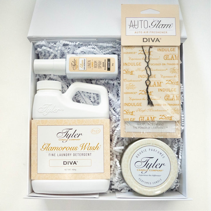 Product photograph of a Tyler Candle Company Diva fragrance gift box featuring the iconic Glamorous Wash detergent, room spray, and a perfumed candle displayed on white shredded paper with elegant gold and ivory packaging