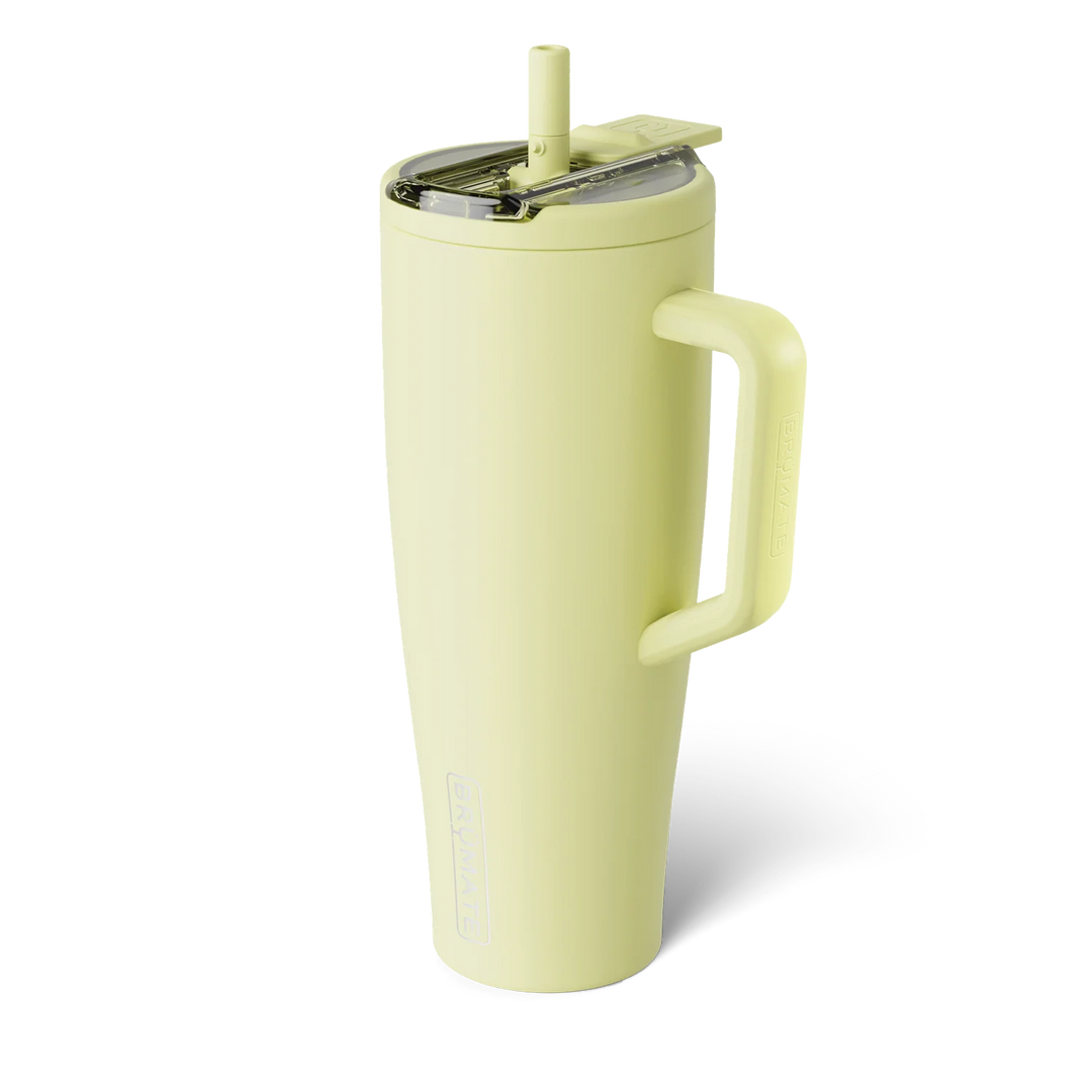 Commercial product photography for BrüMate featuring a citron yellow Era insulated tumbler in a studio setting with a matching straw, transparent leak-proof lid, and large ergonomic handle with debossed branding