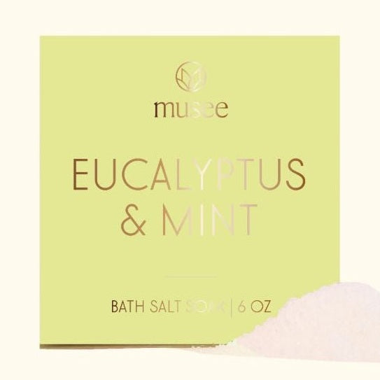 Product photography by Musee of a lime green Eucalyptus and Mint Bath Salt Soak box featuring its gold foil brand logo and a small pile of white crystalline salts on a light cream background