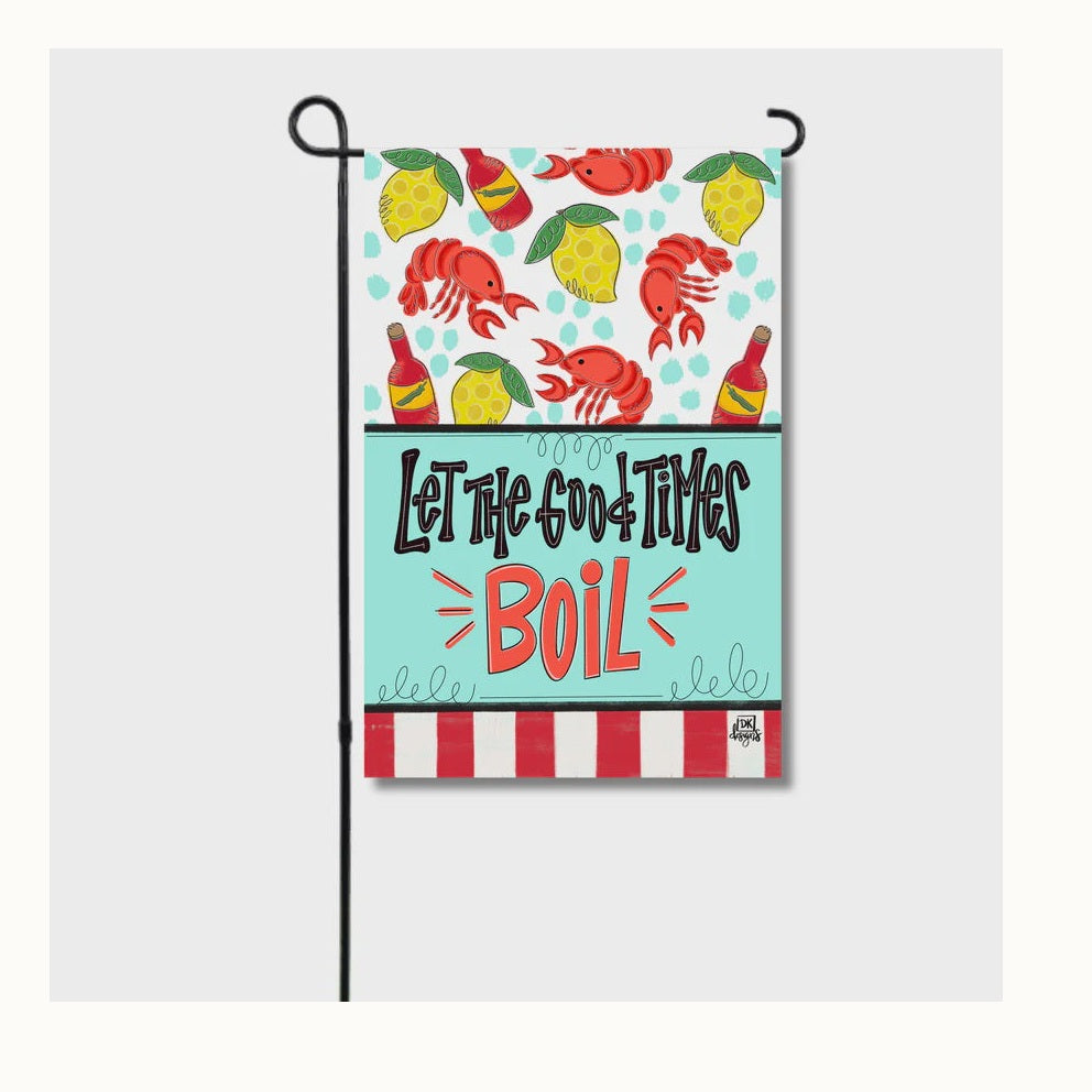 Digital illustration by DK designs of a decorative Louisiana-style garden flag featuring vibrant red crawfish, yellow lemons, and hot sauce bottles with bold typography reading Let the Good Times Boil against a teal and red-striped backdrop