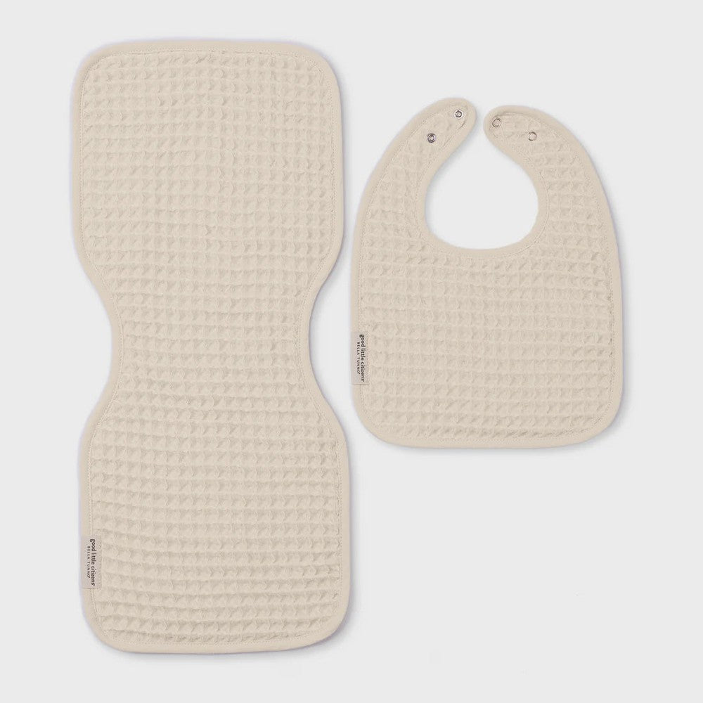 Waffle-knit cotton baby bib and burp cloth set by Bella Tunno displayed on a neutral studio background featuring Good Little Citizens brand labels, cream-colored textured weave, and silver snap closures