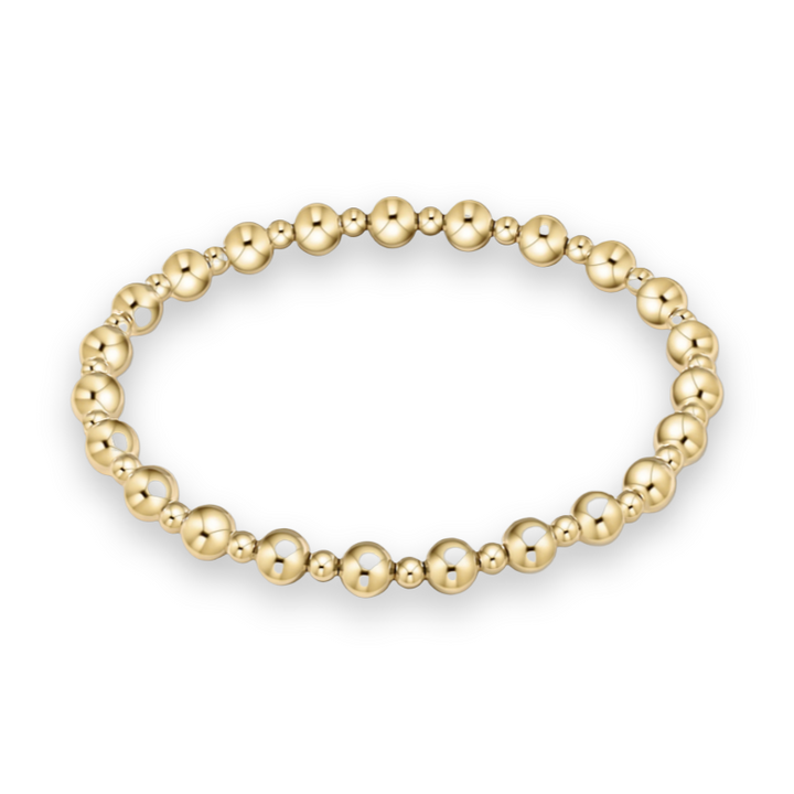 Studio product photograph of a polished gold beaded bracelet centered on a white background featuring alternating large and small spherical beads with a brilliant high-shine reflective finish